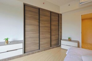 Une chambre à coucher comprenant un lit, une armoire, des tables de chevet et une petite plante sur chaque table.