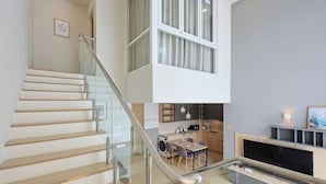 A modern interior with a staircase, a dining area, and a kitchen.