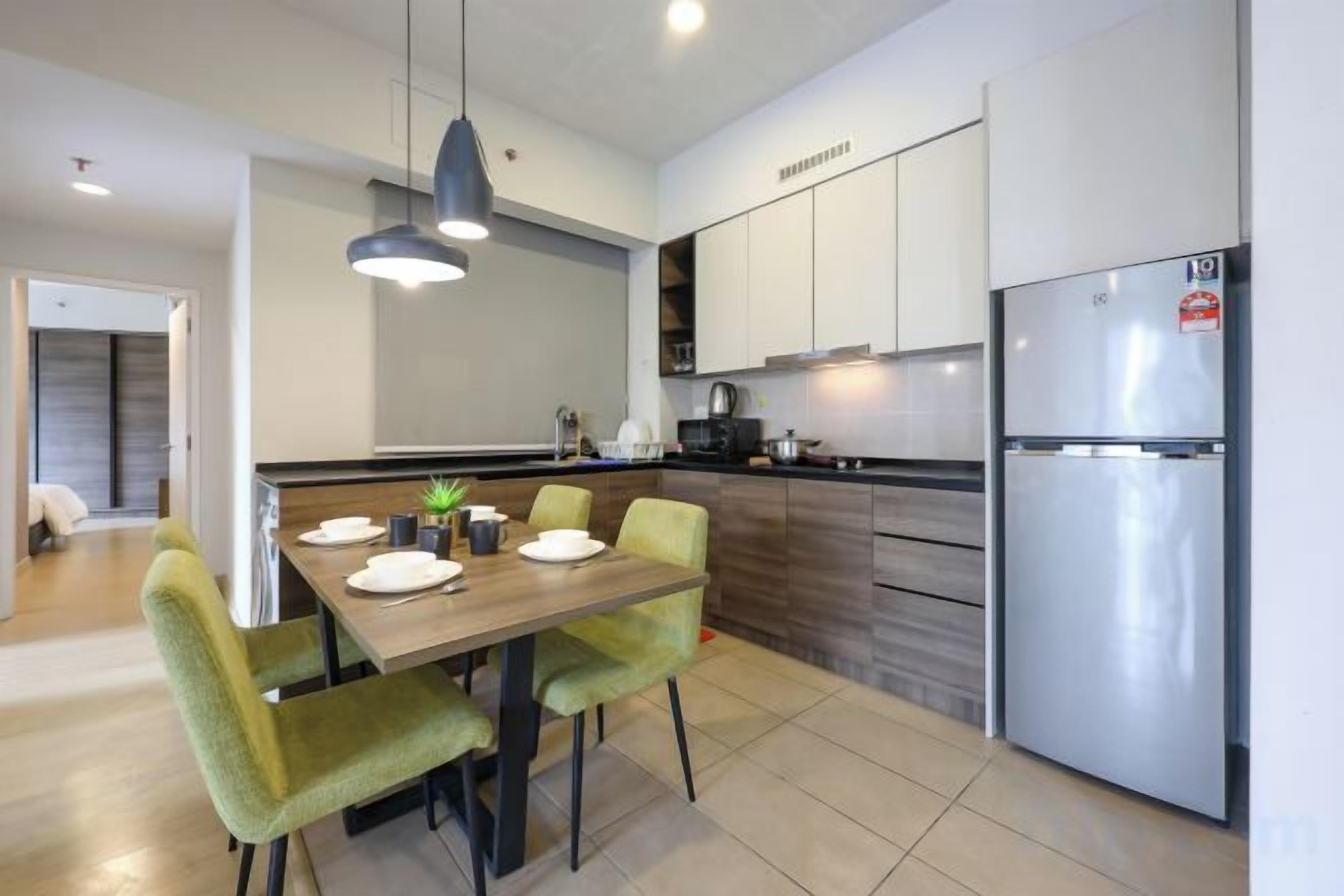 A modern kitchen with a dining table, chairs, a refrigerator, and a pendant light.
