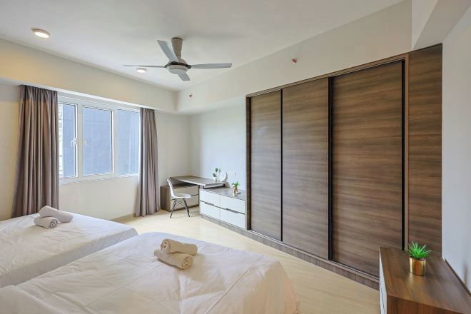 A hotel room with two beds, a desk, a chair, a ceiling fan, and a sliding door.