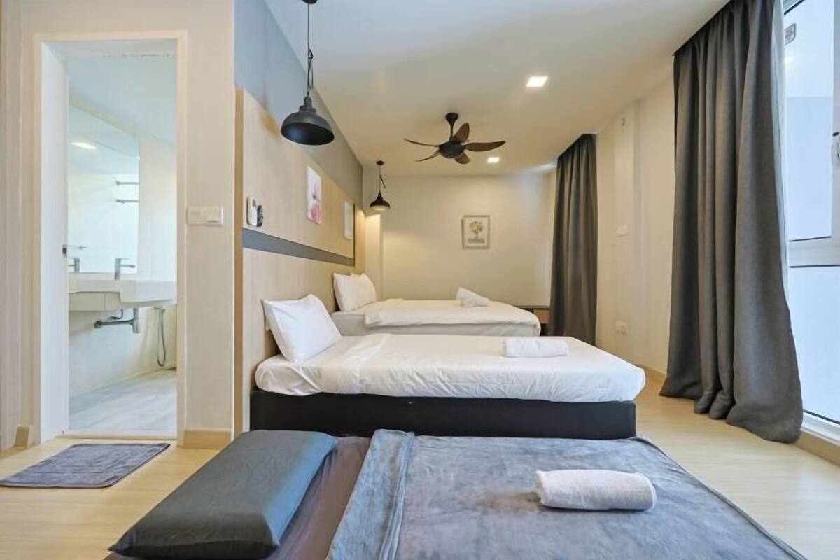 A hotel room with two beds, a ceiling fan, and a view of the bathroom.