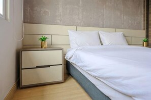 Un dormitorio con cama, mesita de noche y una planta en la pared.