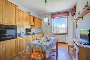 Una cocina con armarios de madera, una mesa de comedor con sillas, un microondas y una ventana con vistas.