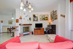 Ein Wohnzimmer mit Kamin, Fernseher, Klavier und Sofa.