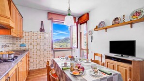 Ein Essbereich mit Tisch für zwei Personen, einem Fernseher und Blick ins Freie.