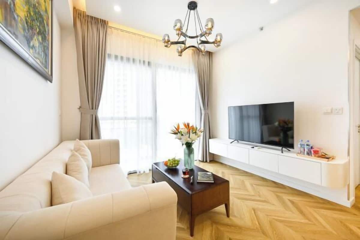 Una sala de estar moderna con un sofá, una mesa de centro, un televisor y un jarrón decorativo.