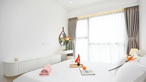 Une chambre d’hôtel comprenant un lit, une table de chevet, une commode, une fenêtre avec des rideaux et un miroir fixé au mur.