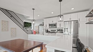 A modern kitchen with white cabinetry, stainless steel appliances, and a central island. - Modern 3BR with Breathtaking Skyline Views (Pittsburgh)