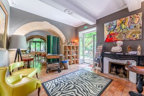 A room with a fireplace, a zebra-patterned rug, a bookshelf, and a painting on the wall. - Room 'Chambre 10' with Shared Pool, Wi-Fi and Air Conditioning (Collias)