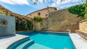 A swimming pool with stone walls and a stone building in the background. - Corail Room with Shared Pool, Wi-Fi & Air Conditioning (Collias)