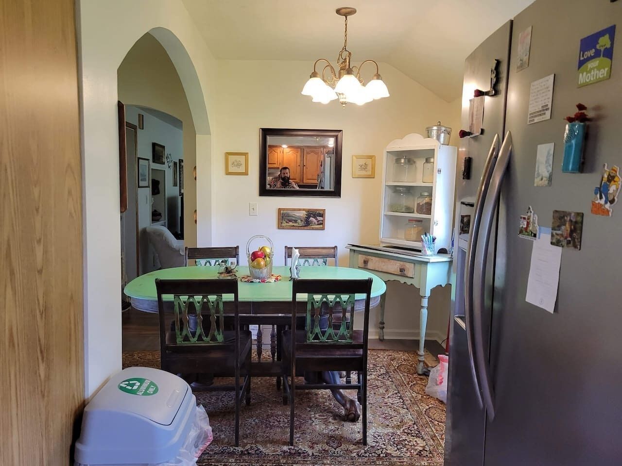 A dining area with a table, chairs, and a refrigerator.