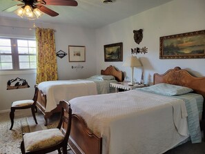 A bedroom with two beds, a chair, a desk, a lamp, and a ceiling fan. - Hot Tub + Fishing Pond + King Suite Retreat (8-10) (Thomas)