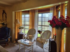 A room with two wicker chairs, a small table, a lamp, and a vase with flowers. - Hot Tub + Fishing Pond + King Suite Retreat (8-10) (Thomas)