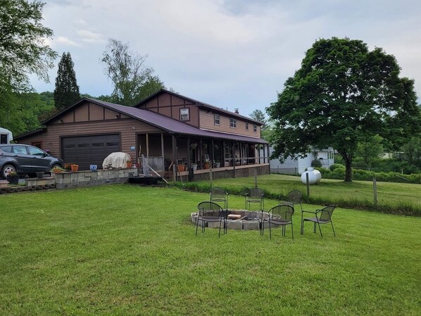 A house with a covered porch, a fire pit, and outdoor seating.