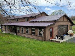 A two-story house with a garage, a covered porch, and a lawn. - Hot Tub + Fishing Pond + King Suite Retreat (8-10) (Thomas)