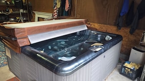 A hot tub with a wooden cover, a control panel, and a small trash bin nearby. - Hot Tub + Fishing Pond + King Suite Retreat (8-10) (Thomas)