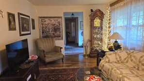 A living room with a television, armchair, sofa, and decorative items.