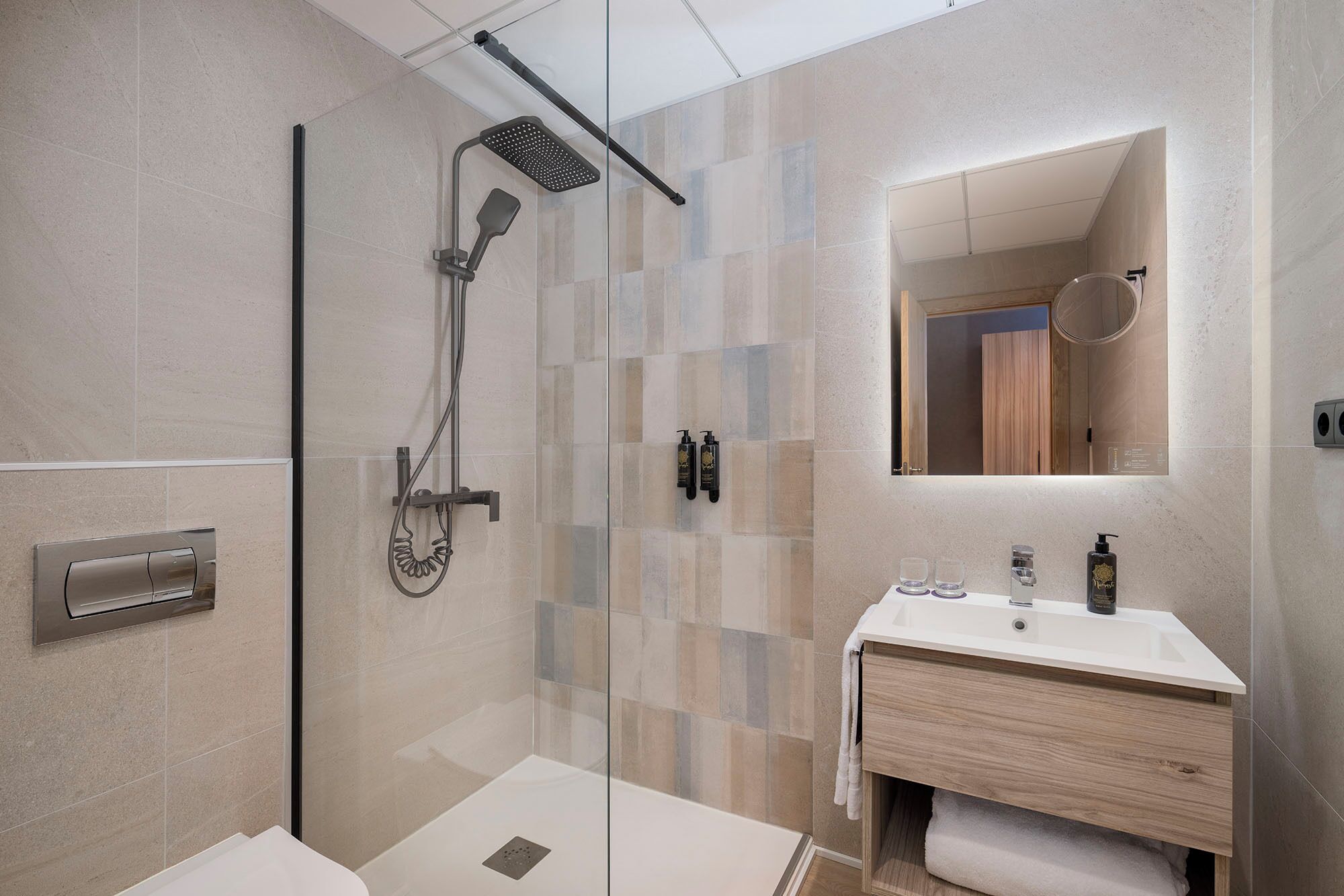 A modern bathroom with a glass-enclosed shower, a vanity with a mirror, and a toilet.