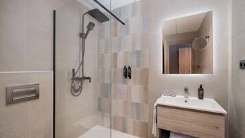 A modern bathroom with a glass-enclosed shower, a vanity with a mirror, and a toilet.