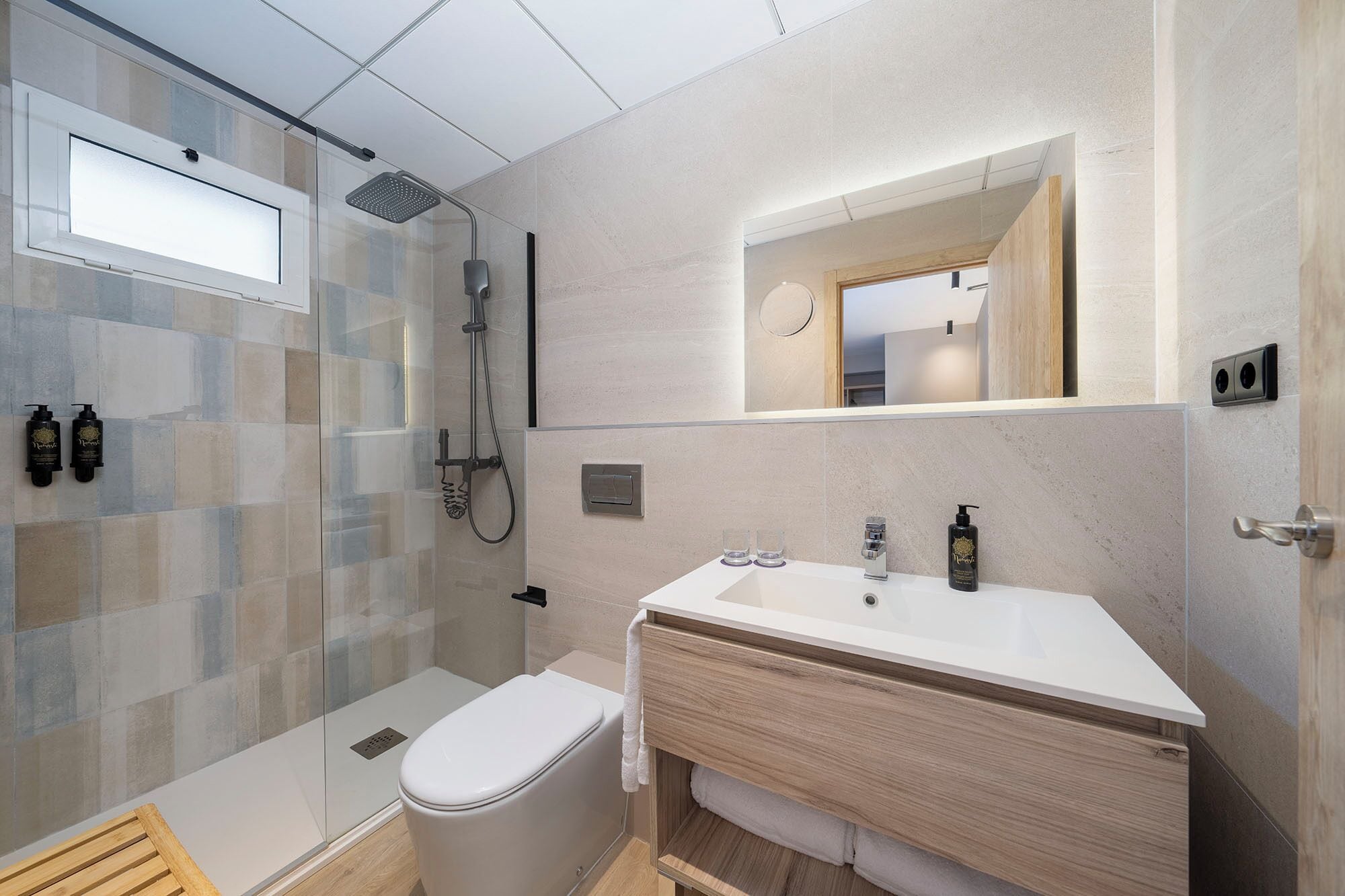A modern bathroom with a glass shower enclosure, a white sink, and a mirror above the vanity.