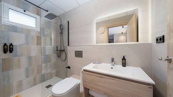 A modern bathroom with a glass shower enclosure, a white sink, and a mirror above the vanity.