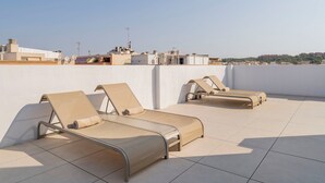Dos tumbonas en una terraza en la azotea con vista a la ciudad.