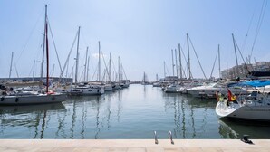 Un puerto deportivo con numerosos veleros amarrados, agua tranquila y cielo despejado.