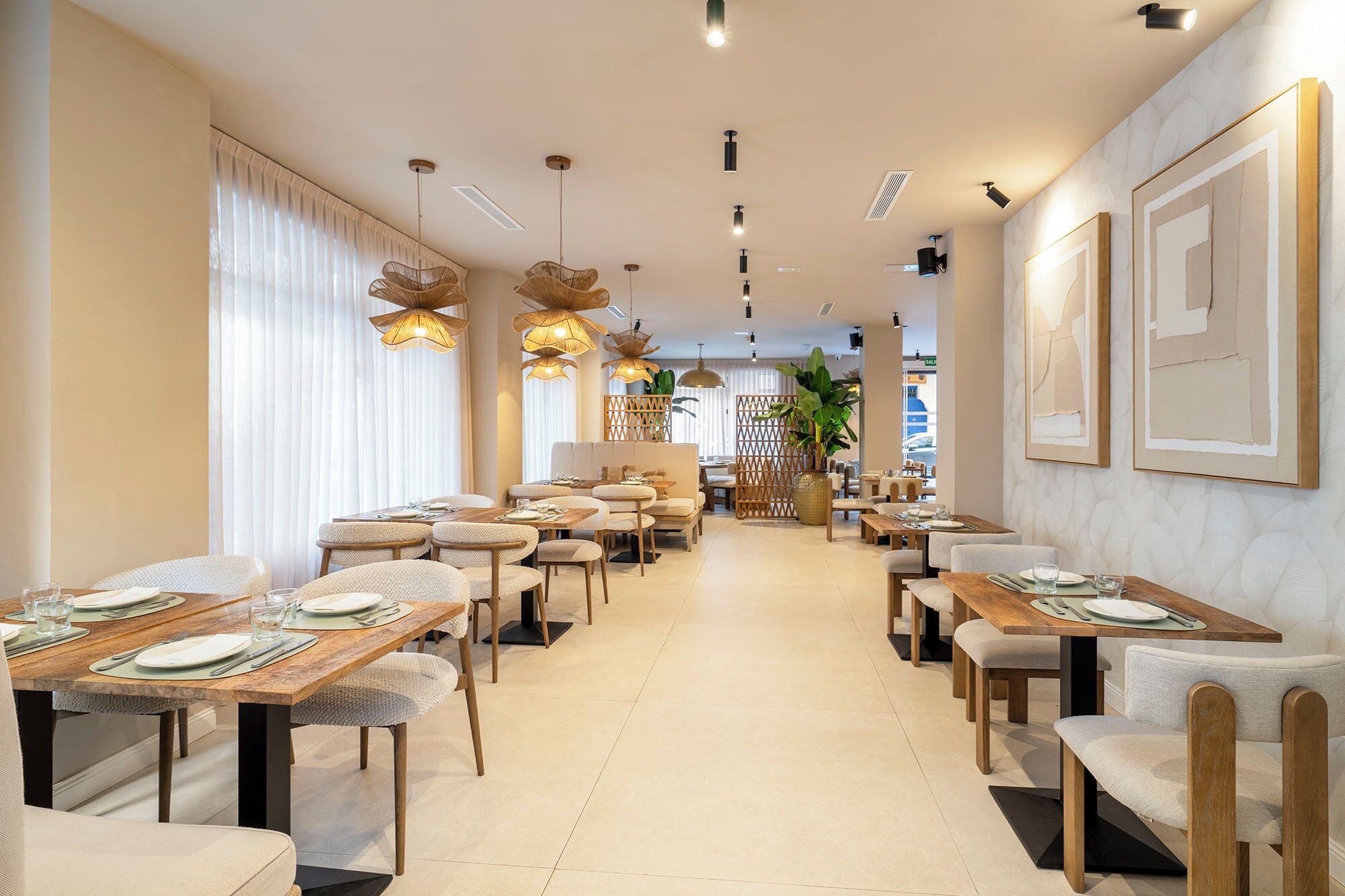 A restaurant with multiple dining tables and chairs, a central walkway, and a view of the street outside.