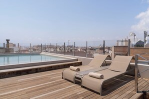 A rooftop pool area with lounge chairs and a cityscape view. - Dorma Gaudea Santa Pola (Santa Pola)