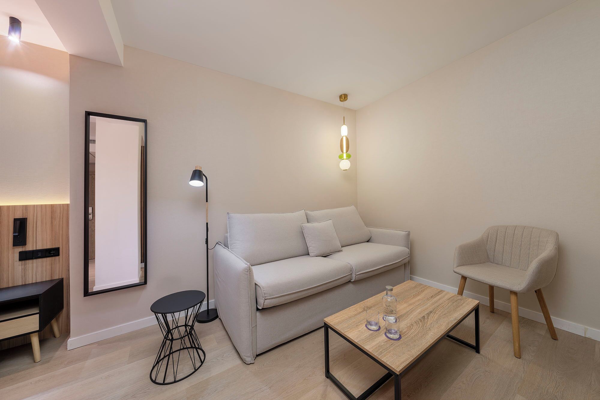 Ein stilvolles Wohnzimmer mit einer Couch, einem Sessel, einem Couchtisch und einer Stehlampe.
