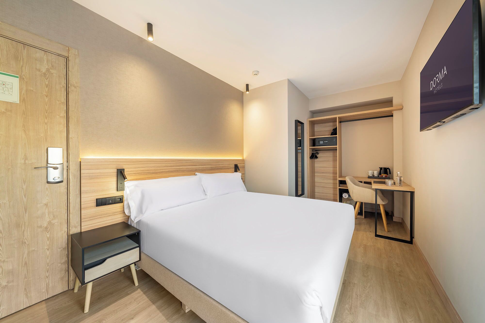 Una habitación de hotel moderna con cama, mesita de noche y escritorio con silla.