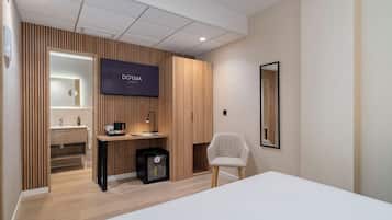 Una habitación de hotel moderna con una cama, un escritorio con ordenador, una silla, un televisor y un armario.