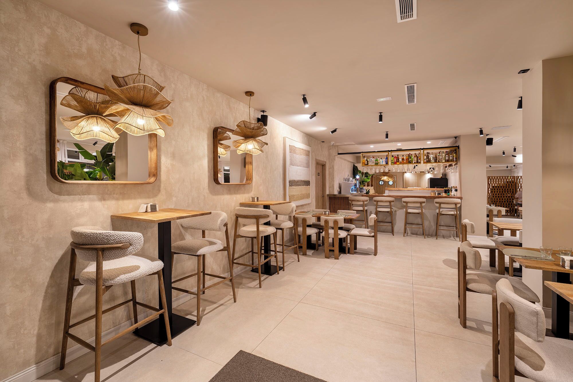 Ein Restaurantinneres mit hohen Tischen, Barhocker und hängenden Leuchten.