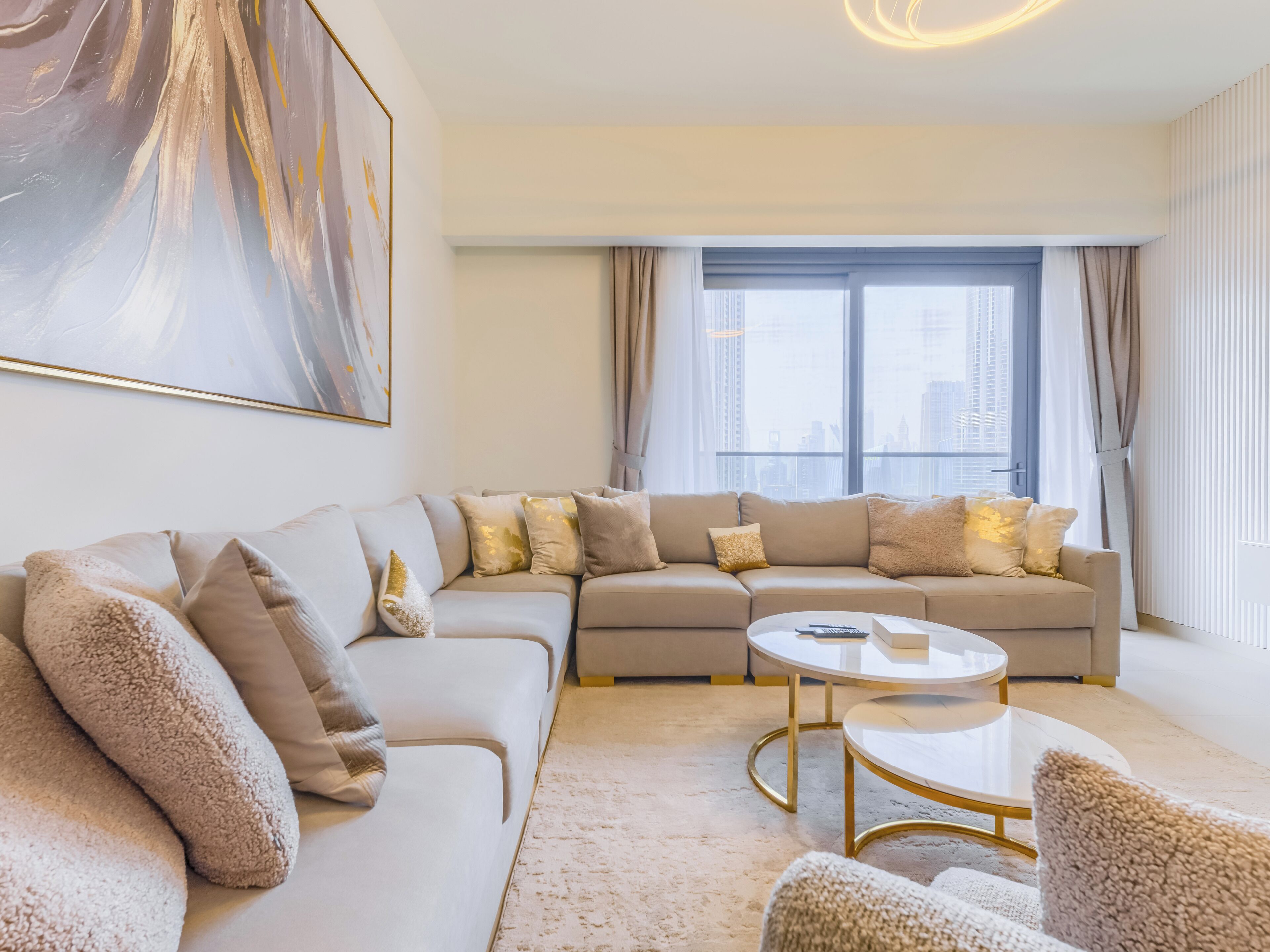 Ein modernes Wohnzimmer mit einem Ecksofa, einem runden Couchtisch und einem großen Fenster mit Vorhängen.