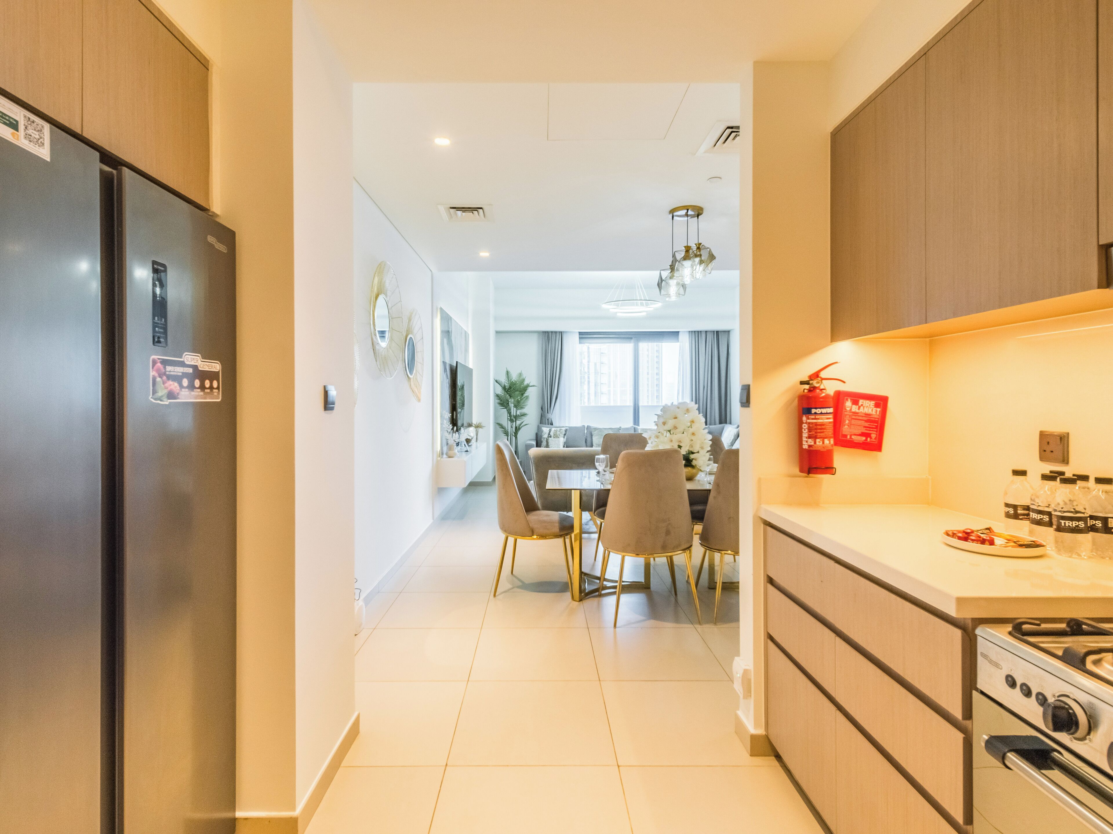 A modern kitchen with a stainless steel refrigerator, a gas stove, and a dining area with a table and chairs.
