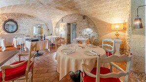 Un restaurante con paredes de piedra, mesas redondas y sillas rojas.