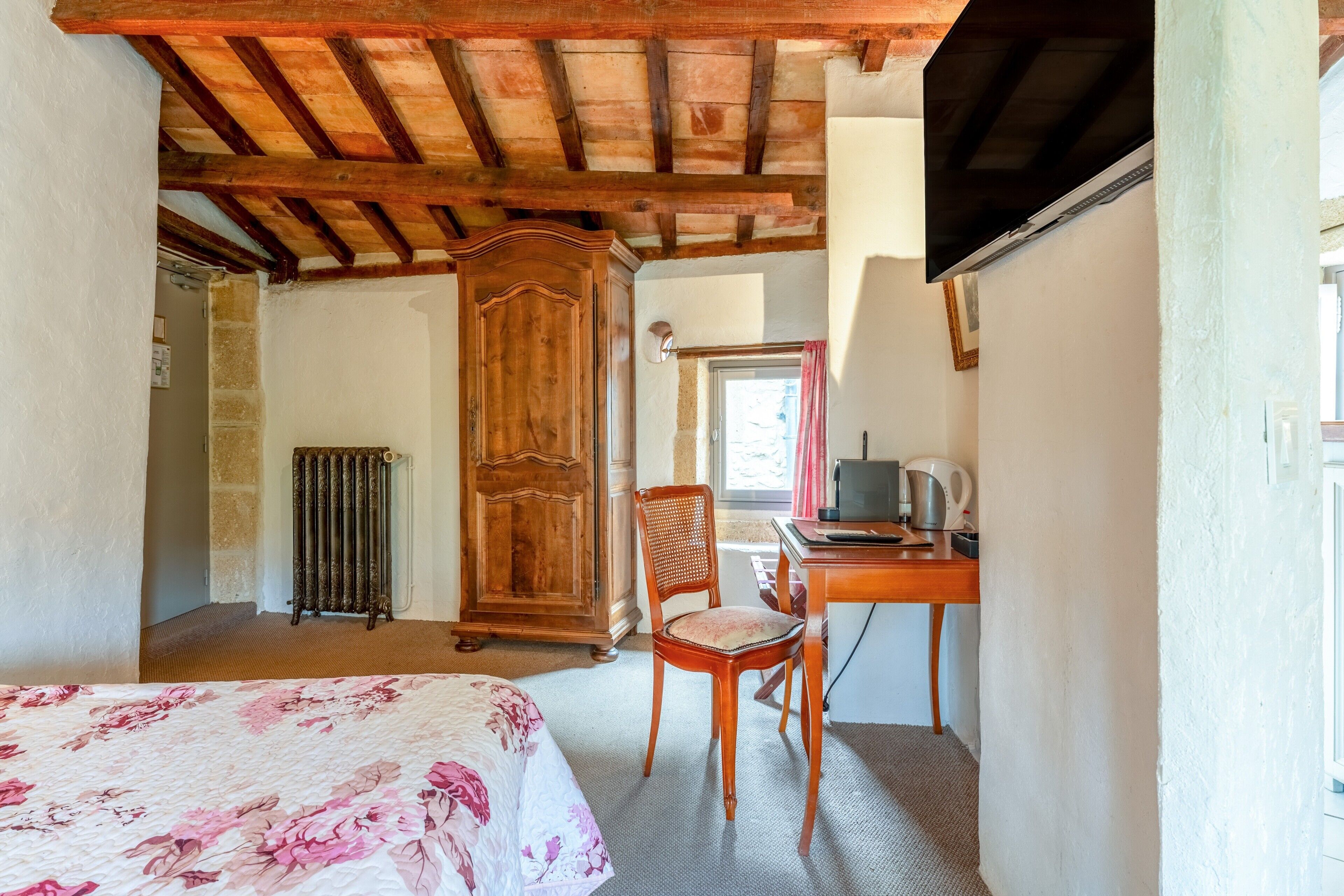 Un dormitorio con cama, armario de madera, silla, escritorio y radiador.