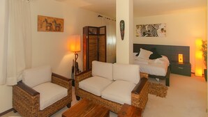 A cozy room with a sofa, two armchairs, a wooden coffee table, a bed with white bedding, and a nightstand with a lamp. - WELCS APARTMENT 284 PDA with terrace and view (Sant Feliu de Guixols)