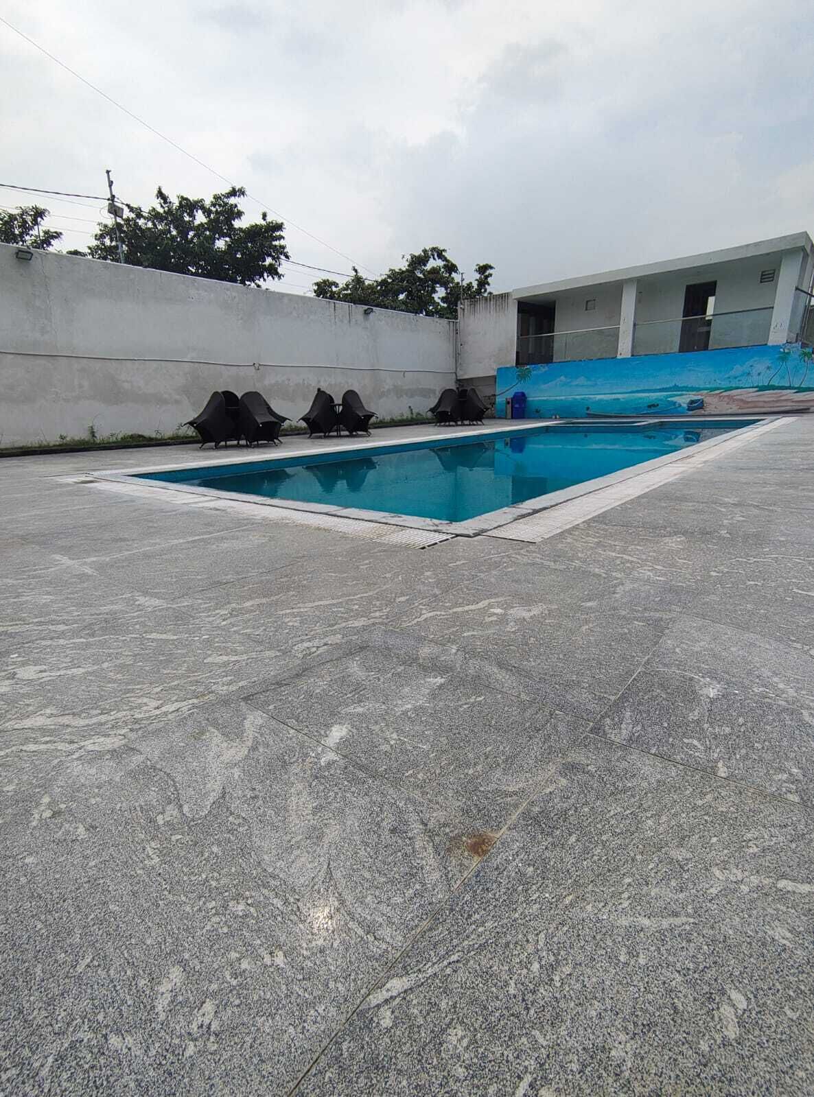 A swimming pool with lounge chairs and a building with a mural in the background.