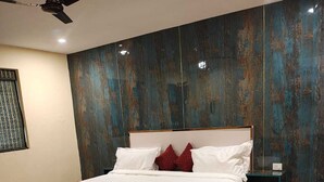 Une chambre à coucher avec un grand lit, un ventilateur de plafond, une table de chevet et une chaise.