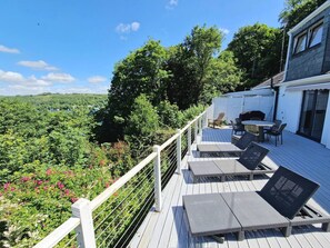 A deck with outdoor furniture, a railing, and a view of a forested landscape. - Three Quarter Cottage (Bodinnick)