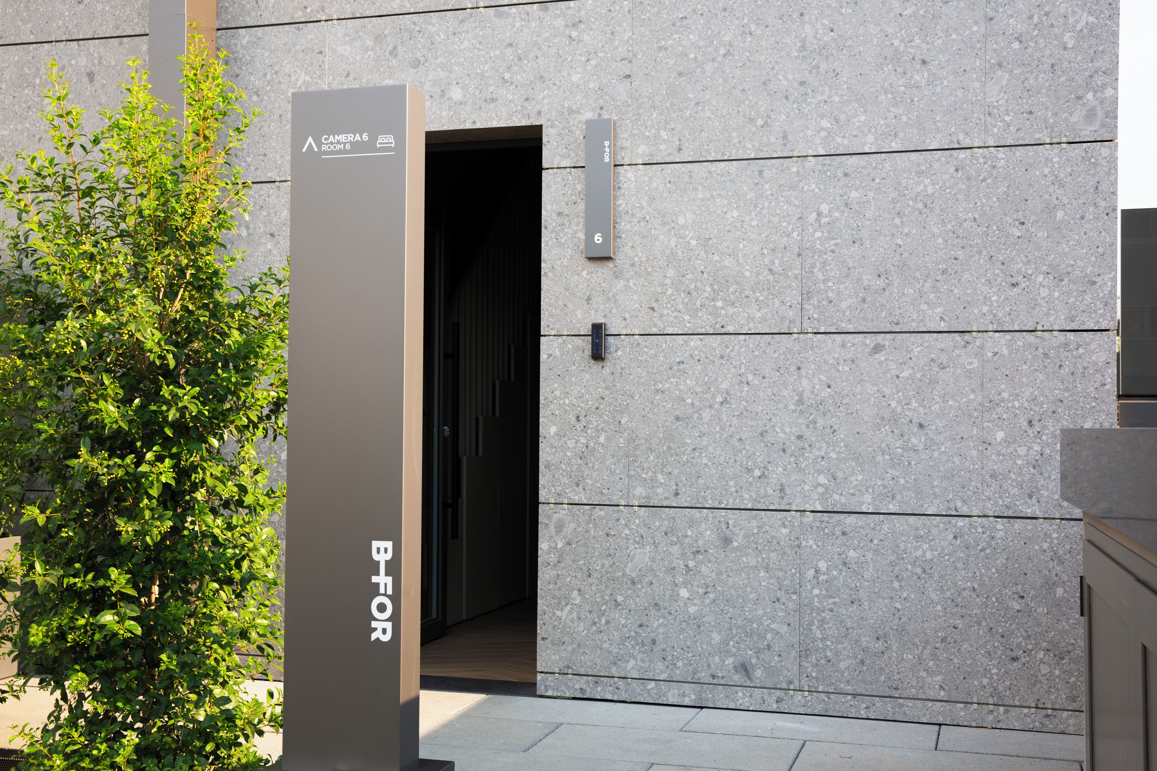 A modern building entrance with a sign for "Camera 6 Room 6" and a door marked with the number 6.