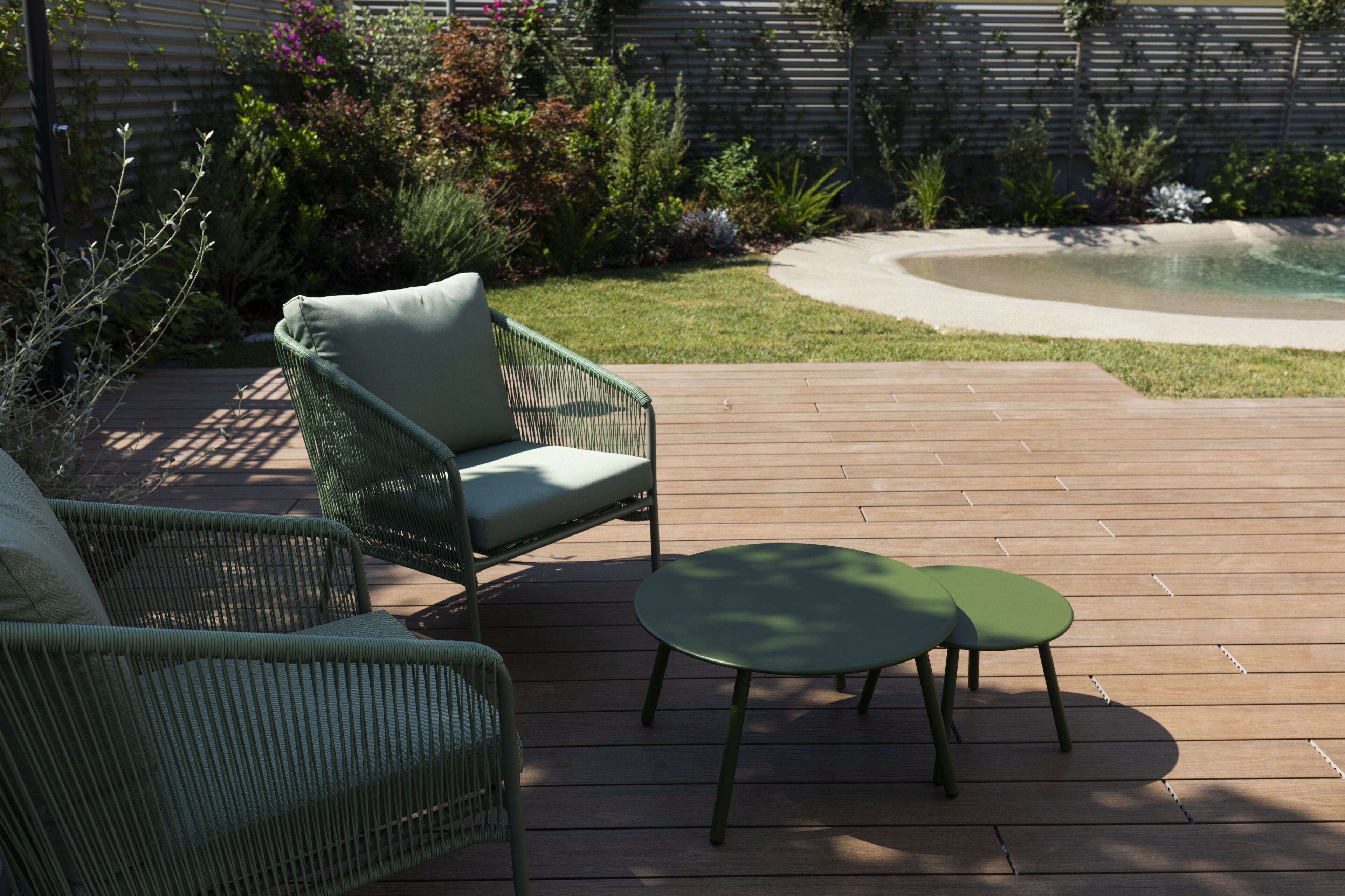 A wooden deck with two green chairs and a small table.