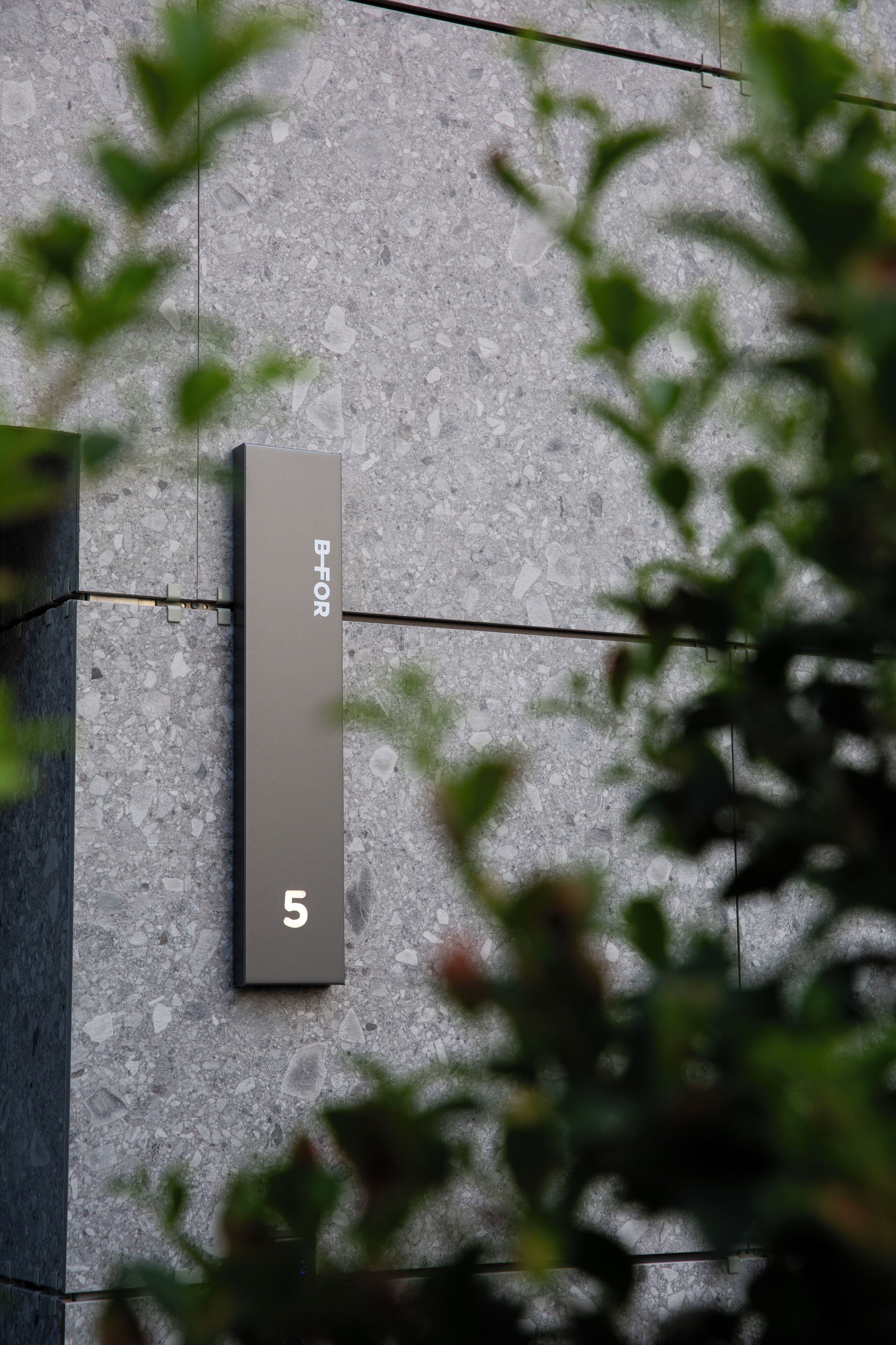 A modern building facade with a textured surface and a rectangular sign with the number 5.