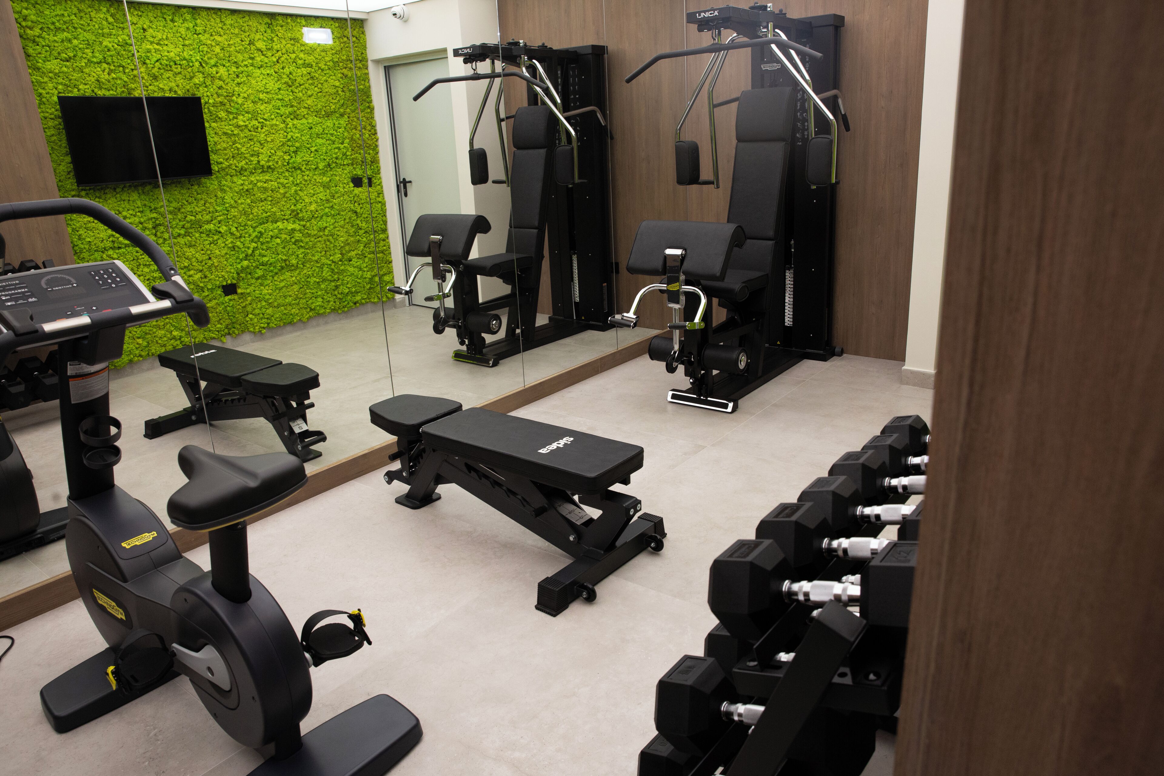 Un gimnasio con equipo de ejercicio, una cinta de correr y una pared verde.
