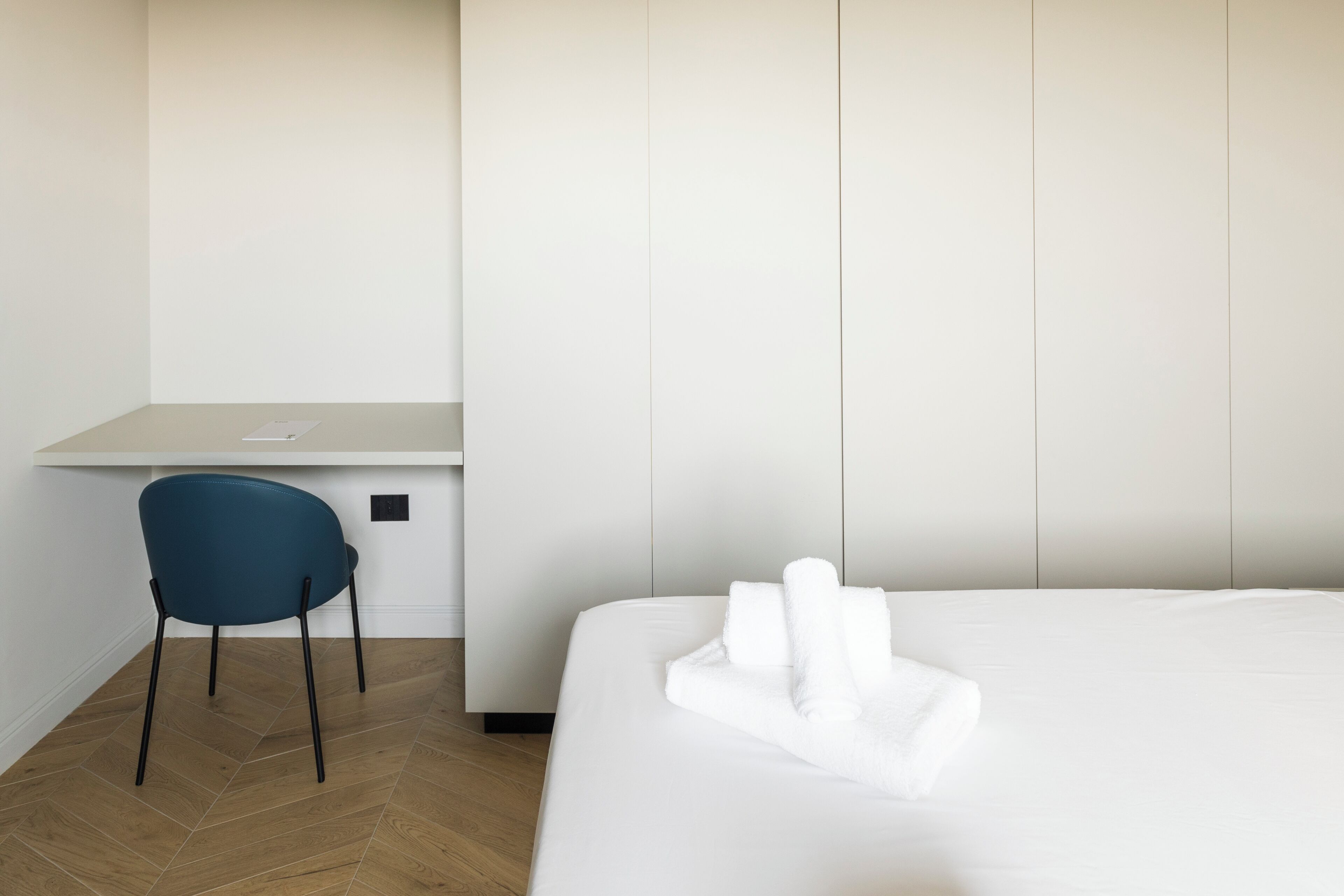 A hotel room with a bed, a desk, and a chair.