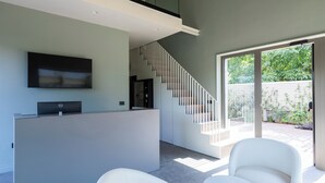 A modern interior with a reception desk, a staircase, and a seating area. - Bfor Suite Experience (Nola)