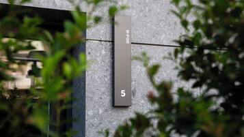 Facciata moderna di un edificio con superficie strutturata e insegna verticale che mostra il numero 5.