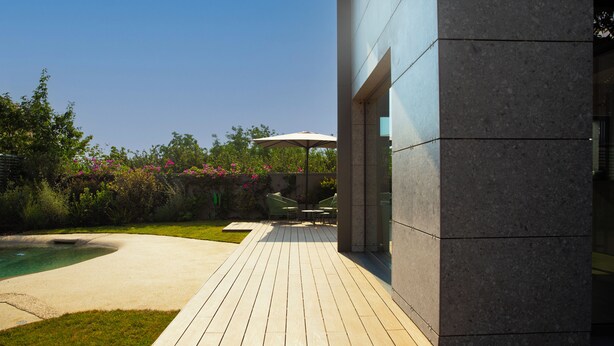 A wooden deck with a pool, outdoor furniture, and a modern building. - Bfor Suite Experience (Nola)