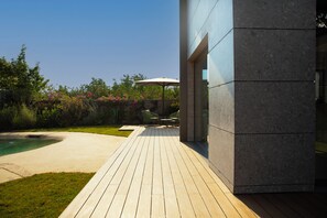 Una terraza de madera con piscina, mobiliario exterior y un edificio moderno.